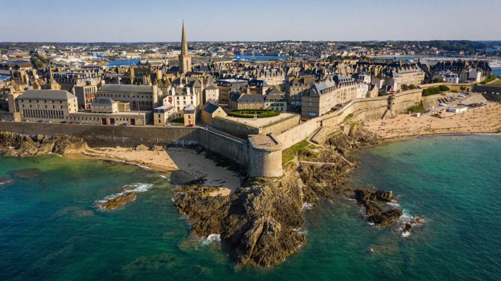 Vue aérienne de Saint-Malo avec ses remparts, ses plages et la mer, illustrant une destination idéale pour un séjour malin et la recherche d’hôtels pas chers pour profiter de la ville.