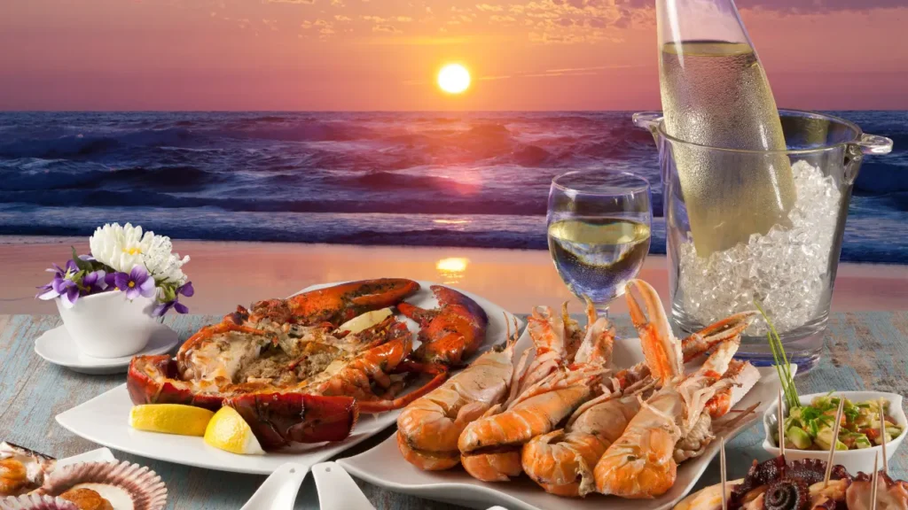 Plateau de fruits de mer face au coucher de soleil à Saint-Malo, homard et langoustines accompagnés de vin blanc sur la côte bretonne.